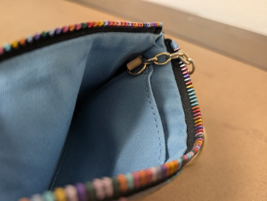 Dooney & Bourke monogram wristlet featuring iconic rainbow zipper and heart charm